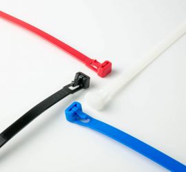 A white, a black, a red and a blue releasable cable tie on a white background.