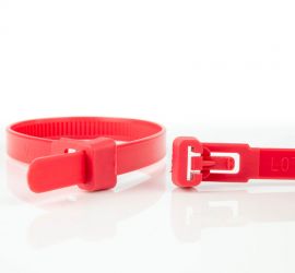 A releasable red plastic cable tie, next to the enlarged head of another red releasable cable tie.