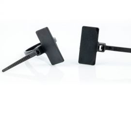 Two black plastic marker cable ties, with the label above the head of the cable tie, of which one is loose, and one is closed.