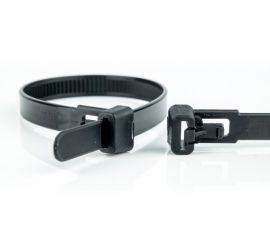 A releasable black plastic cable tie, next to the enlarged head of another black releasable cable tie.